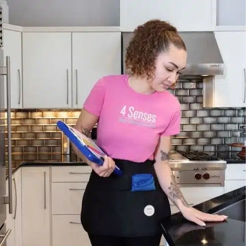 A 4 Senses technician cleaning a kitchen in a pink 4 Senses shirt