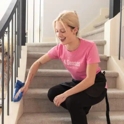 A 4 Senses technician wiping a staircase railing by hand